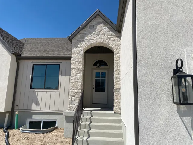 Stone archway entry featuring a white paneled front door with an arched transom window