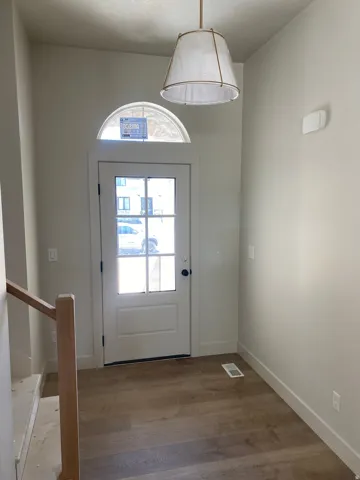 Entryway featuring a glass-paneled door with an arched transom window, wood-finish flooring, and a contemporary pendant light fixture