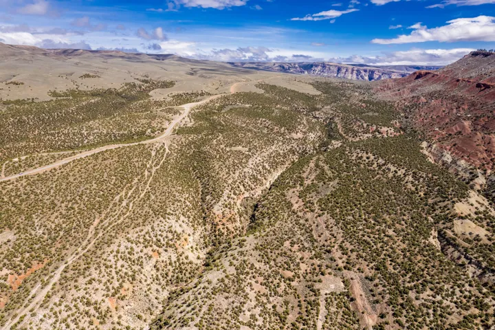 Expansive desert terrain featuring varied topography, natural vegetation, and distant bluffs under a clear sky