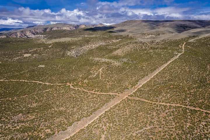 Expansive, undeveloped terrain featuring natural vegetation and distant mountain ranges