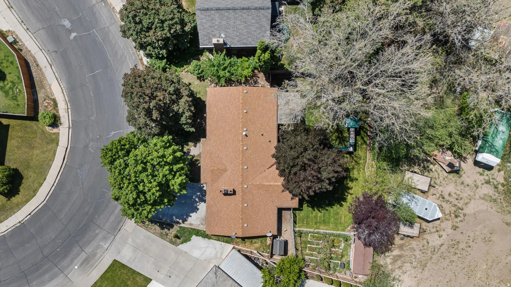 Residential property with a brown shingle roof and surrounding mature trees
