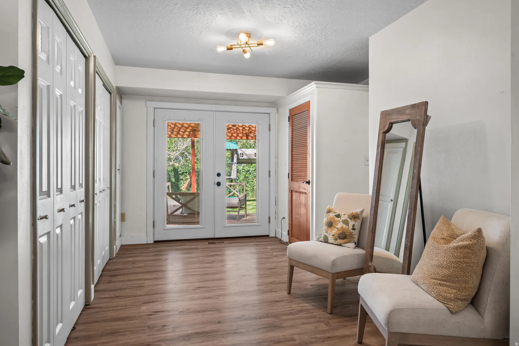 Wood-finish flooring extending throughout, complemented by white walls and a contemporary ceiling light fixture