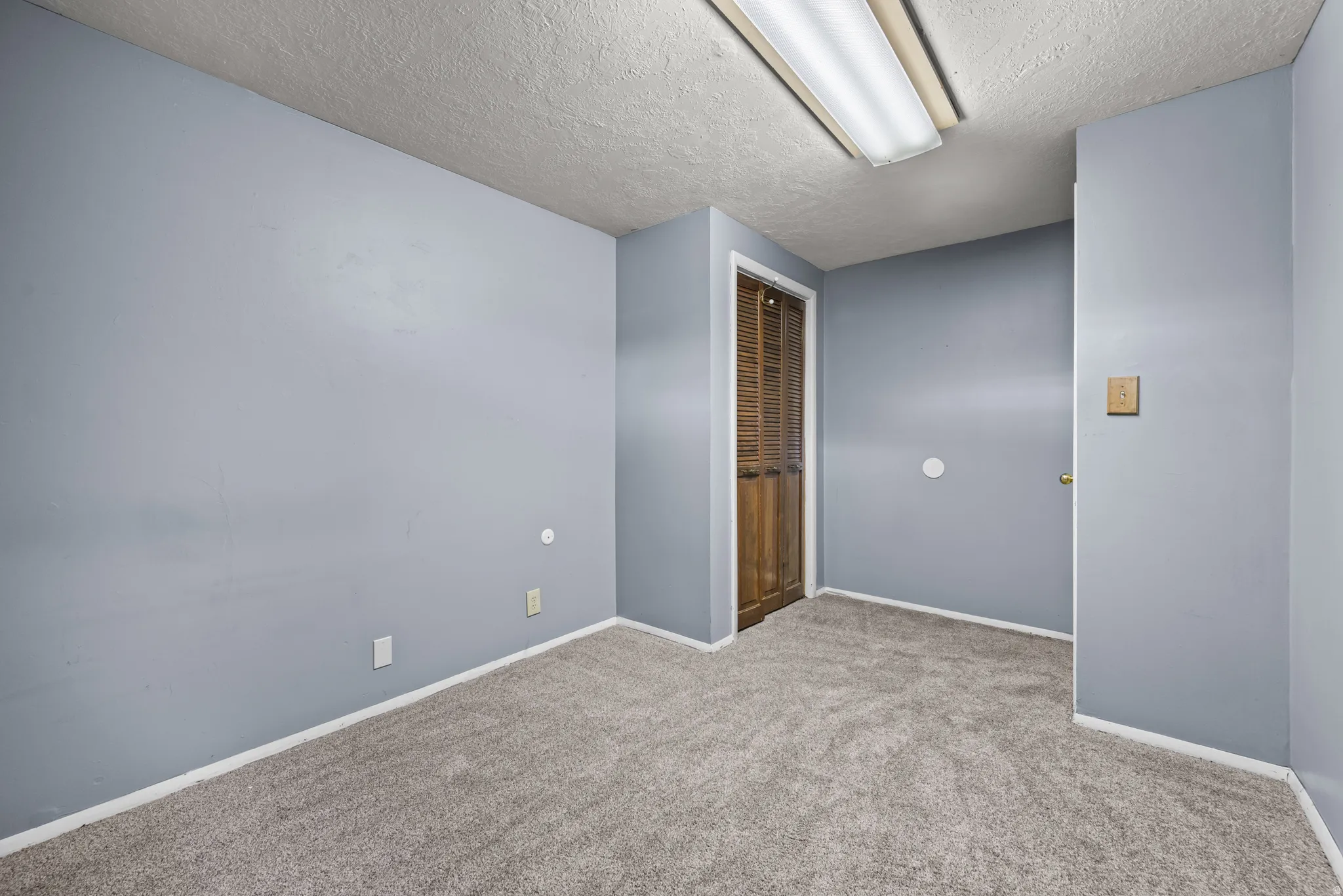 Room featuring light gray walls, gray carpet, and white baseboards