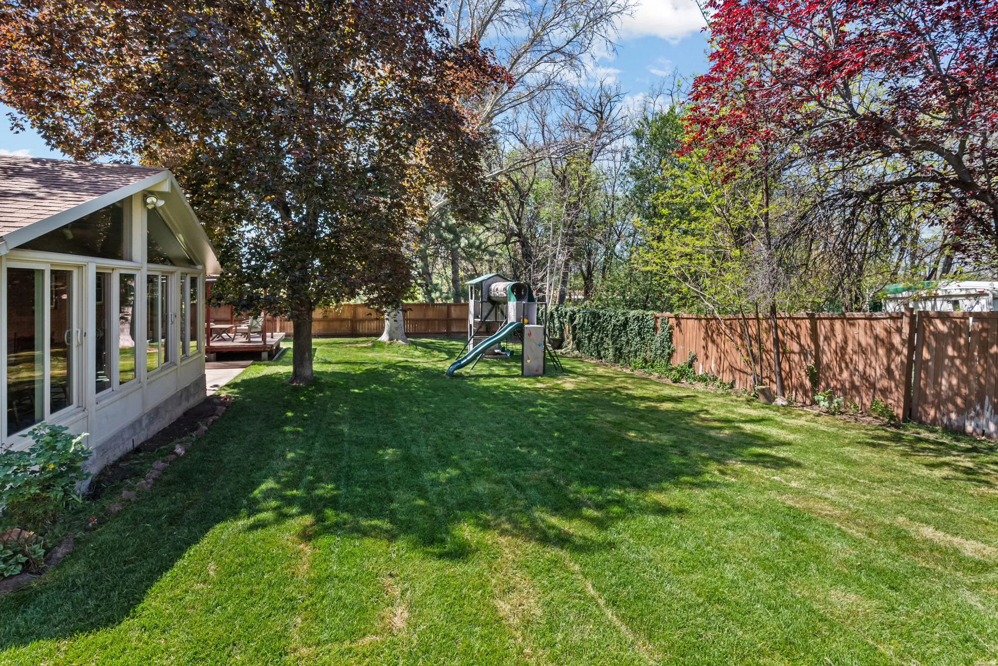 Expansive lawn bordered by mature trees and a privacy fence