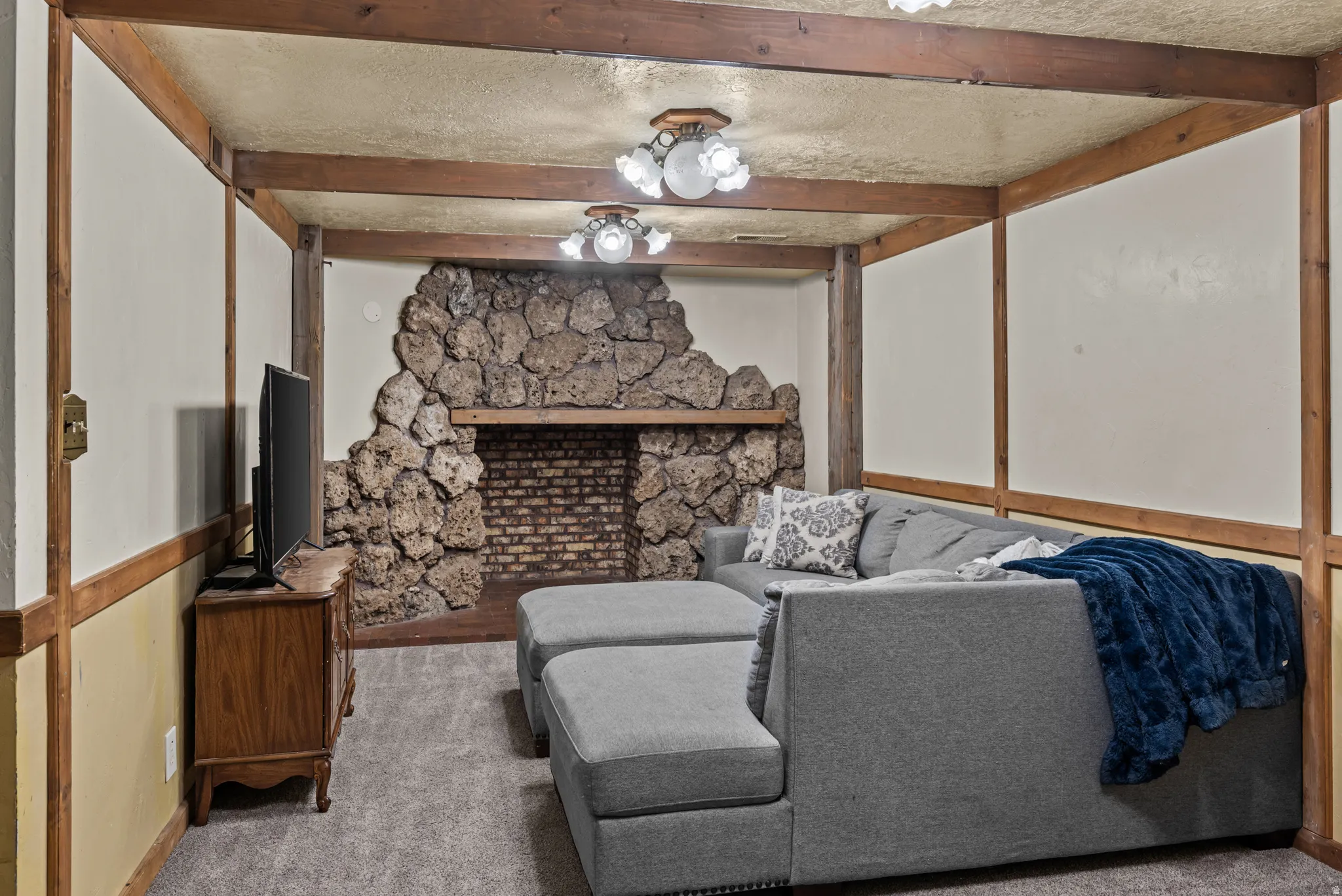 Textured stone fireplace with a brick firebox and wood mantle