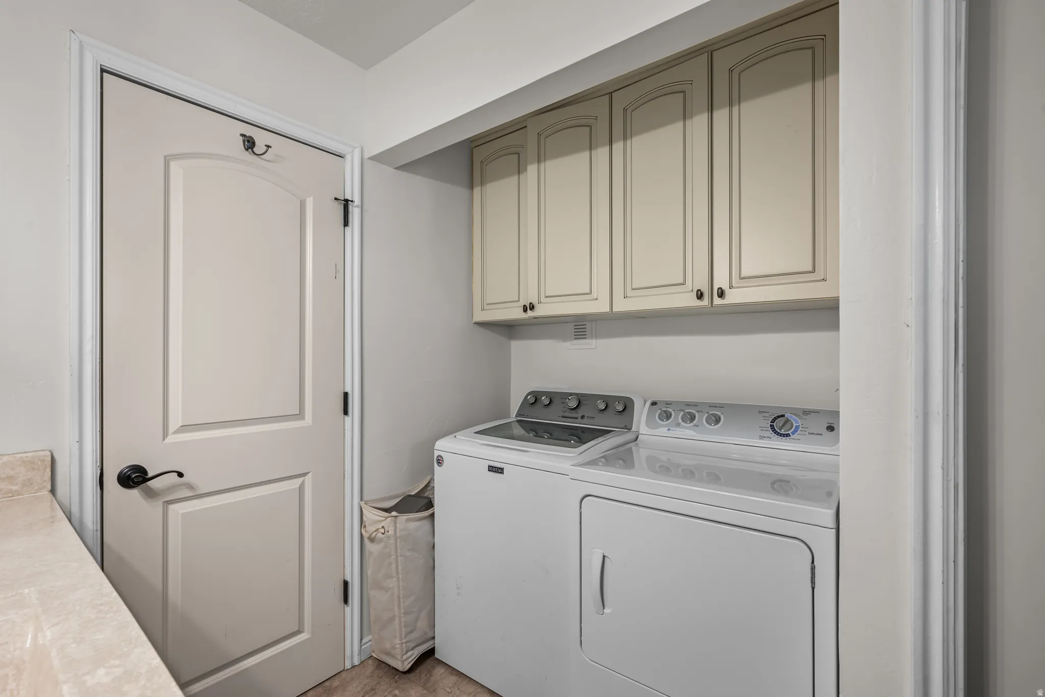 Dedicated laundry area featuring upper cabinetry, a built-in countertop, and wood-finish flooring