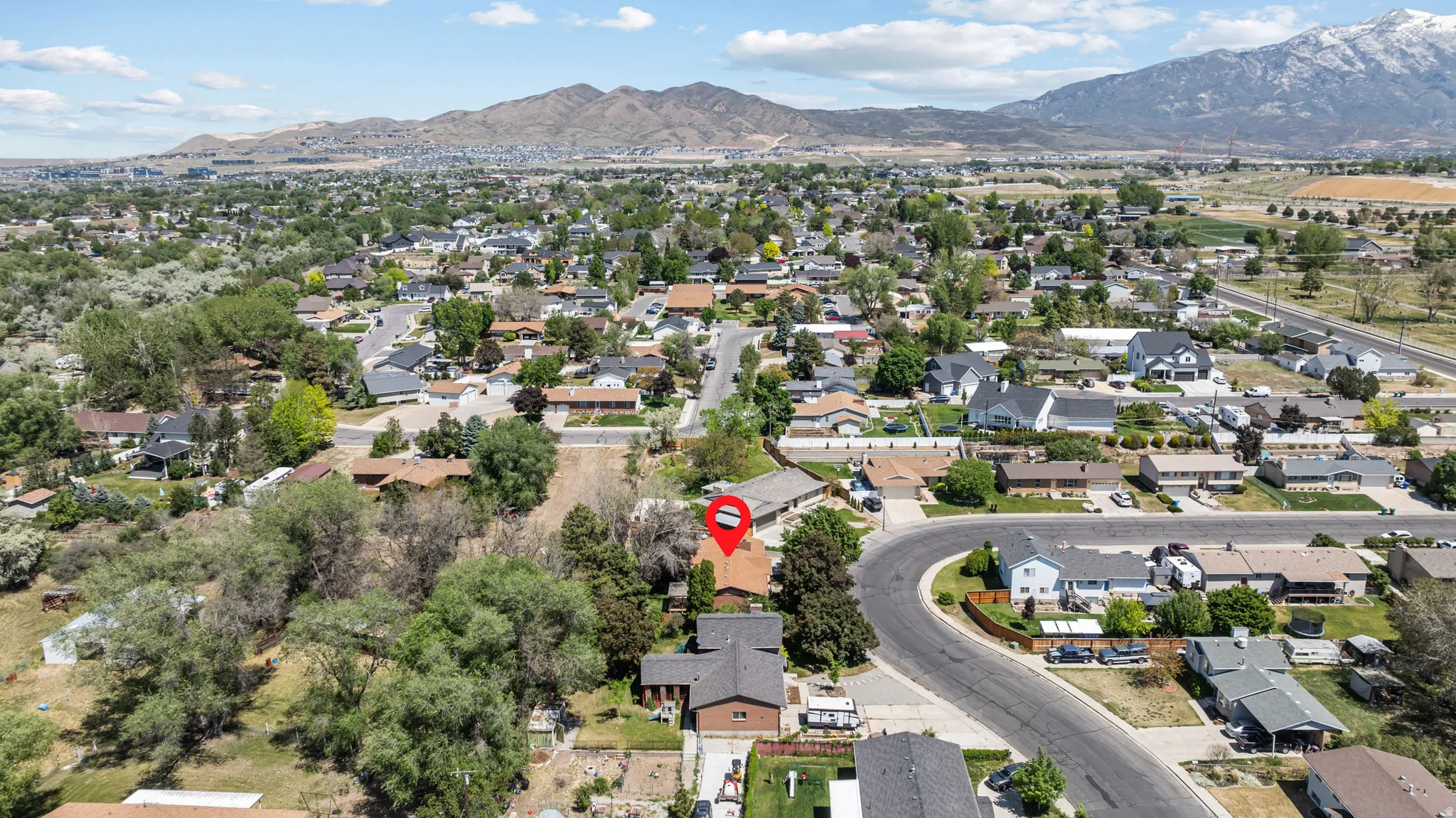 Residential property situated within a developed neighborhood, featuring a prominent red roof and mature trees