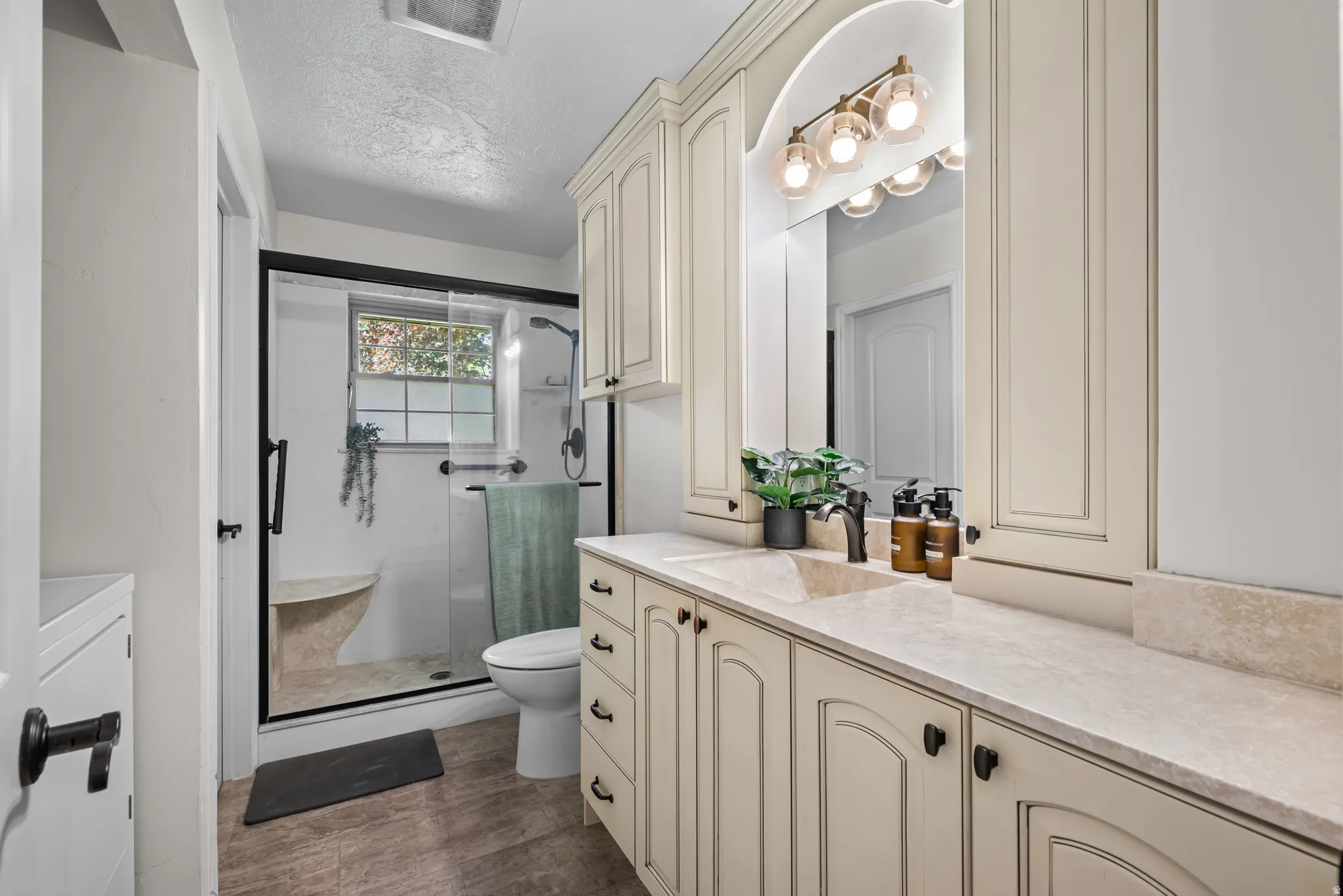 Bathroom featuring a spacious vanity with extensive cabinetry, a built-in sink, and a multi-bulb light fixture