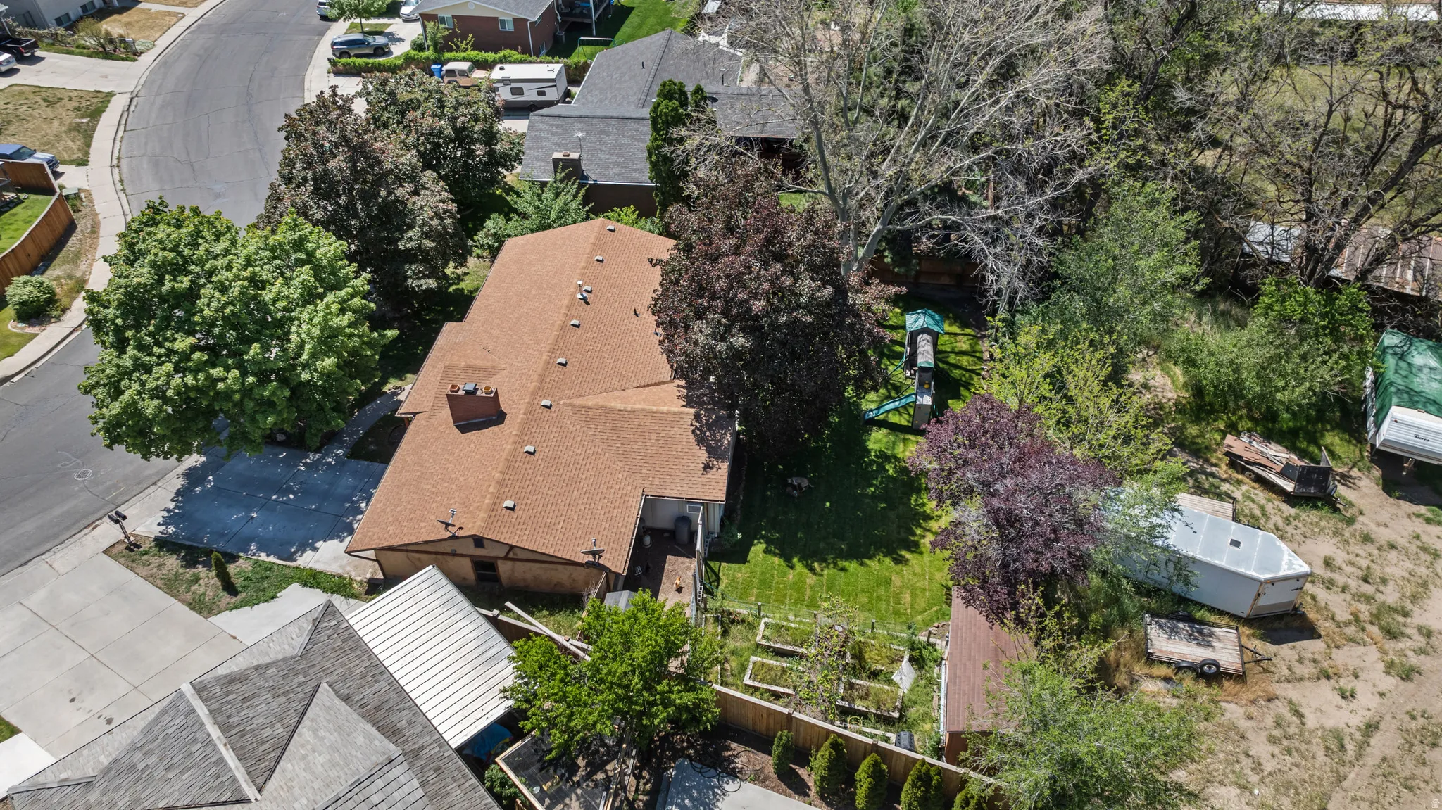 Expansive property featuring a shingle roof, mature trees, a manicured lawn, and a paved driveway