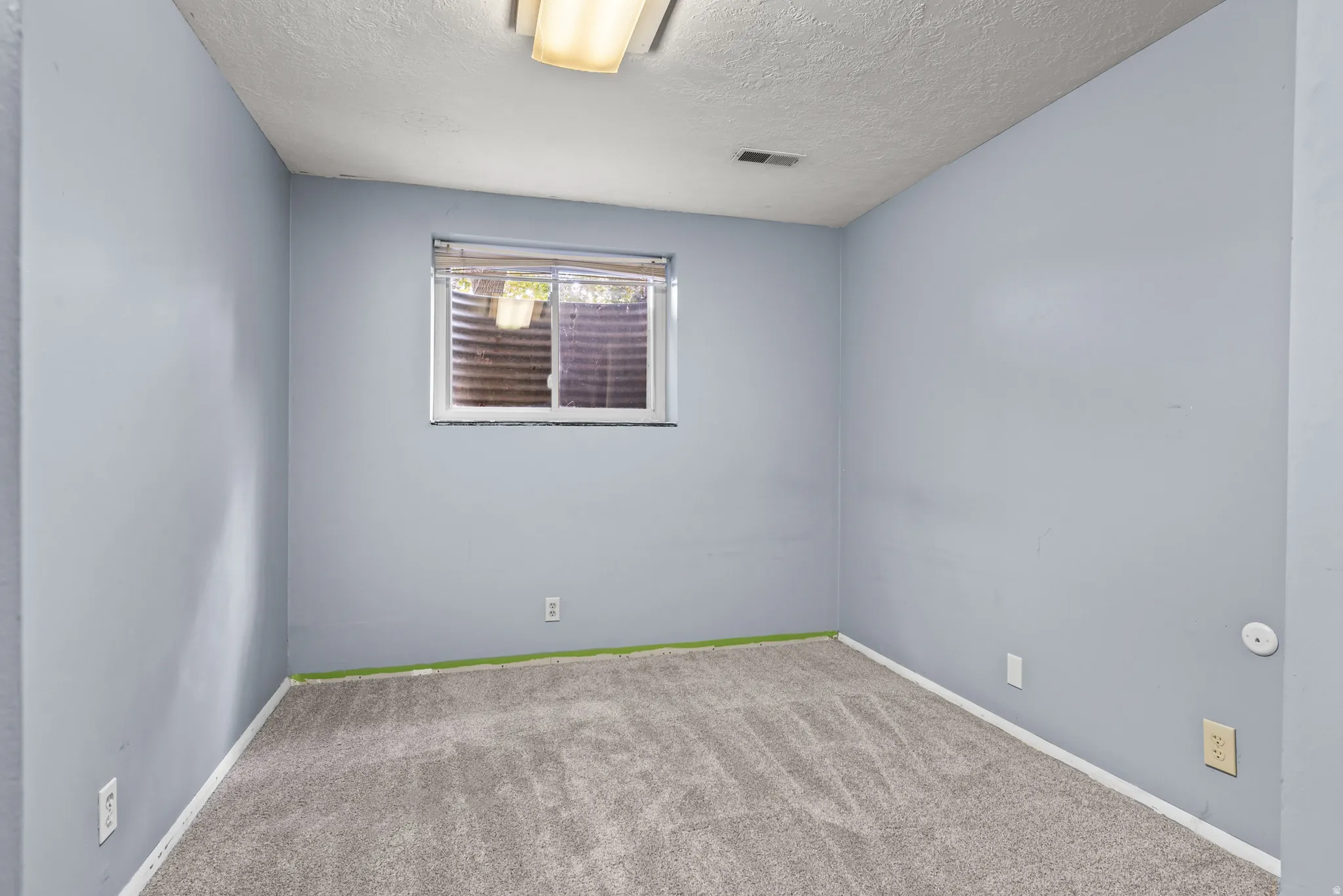 Light gray wall paint, gray textured carpet, and a horizontal window with blinds