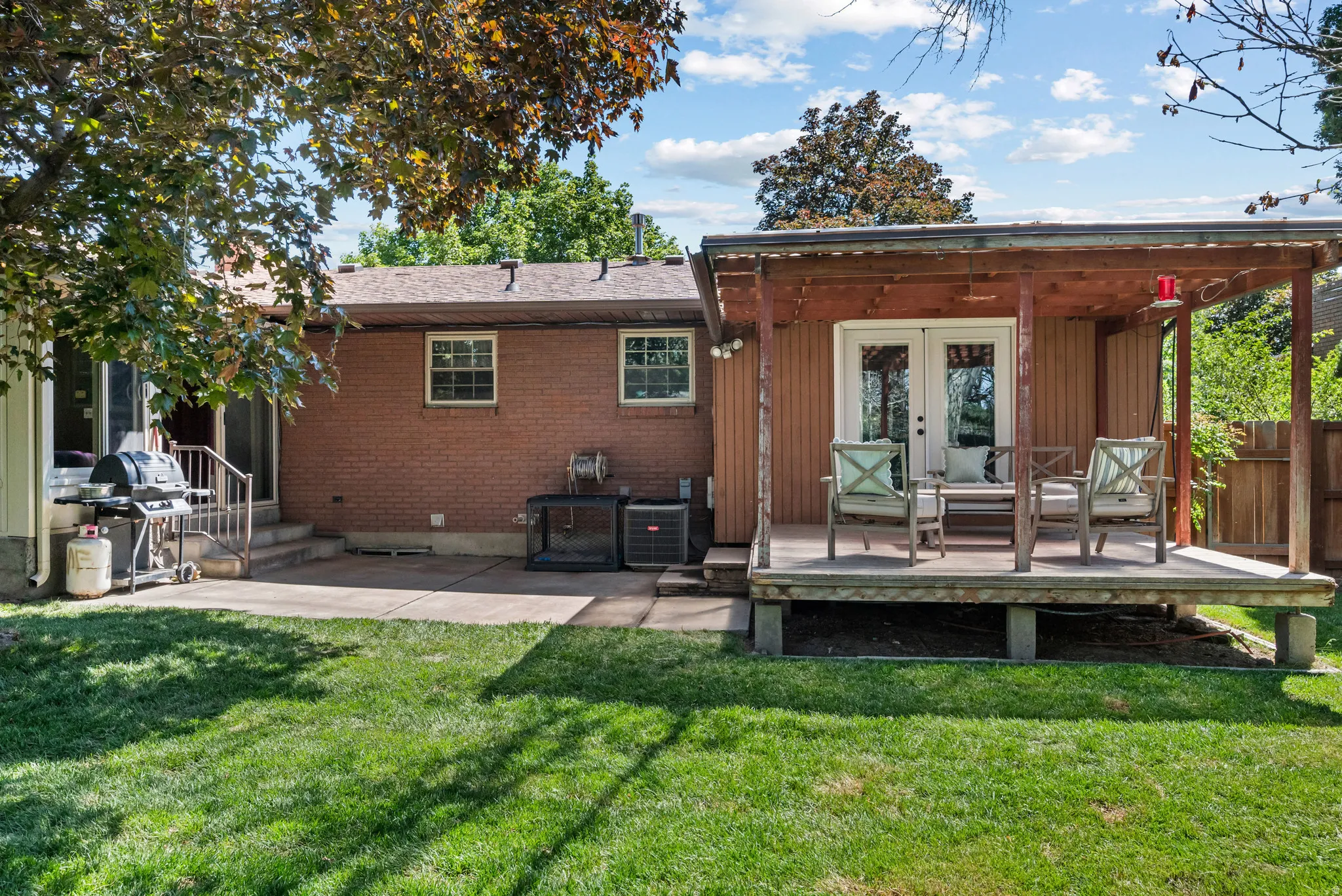 Covered deck with wooden ceiling features double white French doors, providing access to the interior