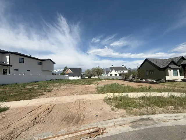 Level building lot featuring a concrete sidewalk and curb along the street frontage
