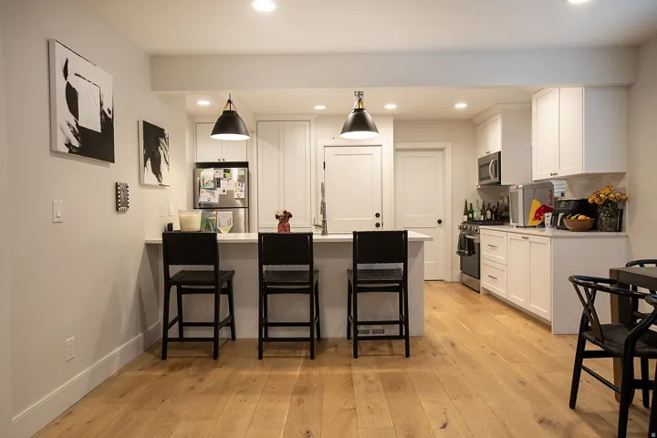 Modern kitchen featuring wood-finish flooring, white cabinetry, recessed lighting, and a kitchen island with pendant lighting