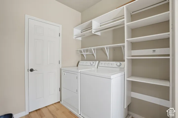 Dedicated laundry off the kitchen, featuring wood-finish flooring, white paneled door, built-in shelving, and hanging rods