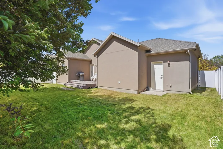 Expansive backyard featuring a manicured lawn, a white picket fence, and a private wooden deck for a back patio. Perfect for bbqs and summer hangs.