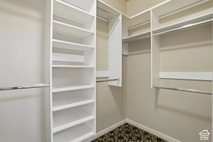 Custom closet system in owners suite, featuring multiple white shelving units and chrome hanging rods