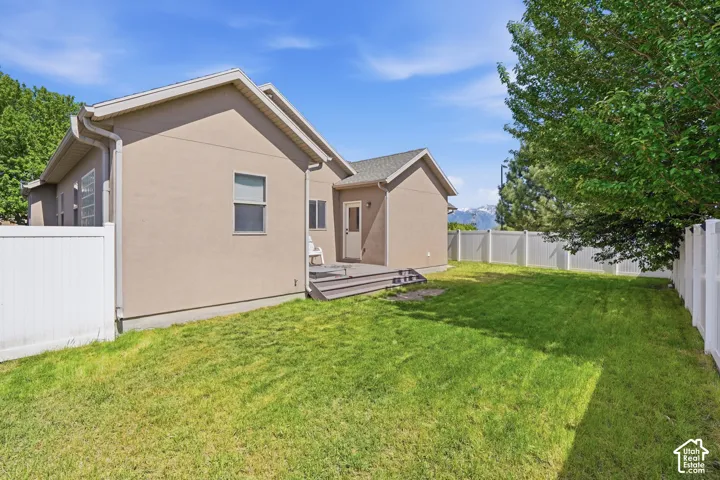 Backyard with newly installed fence. Expansive green lawn with a white vinyl privacy fence