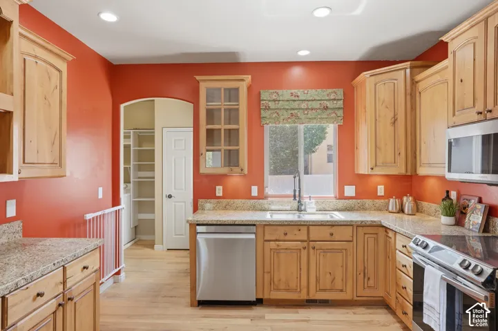 Kitchen featuring light wood cabinetry, stone-finish countertops, stainless steel appliances, and wood-finish flooring