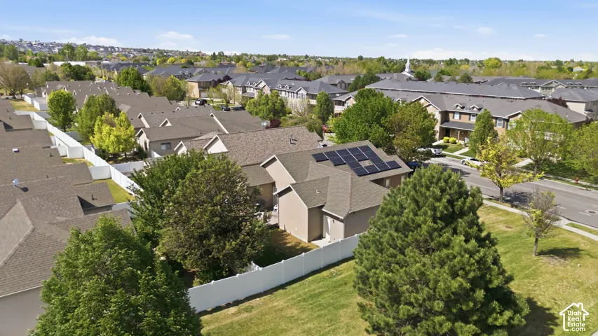 Single-story residence featuring solar panels, a gabled roofline with asphalt shingles, and a light-colored exterior finish