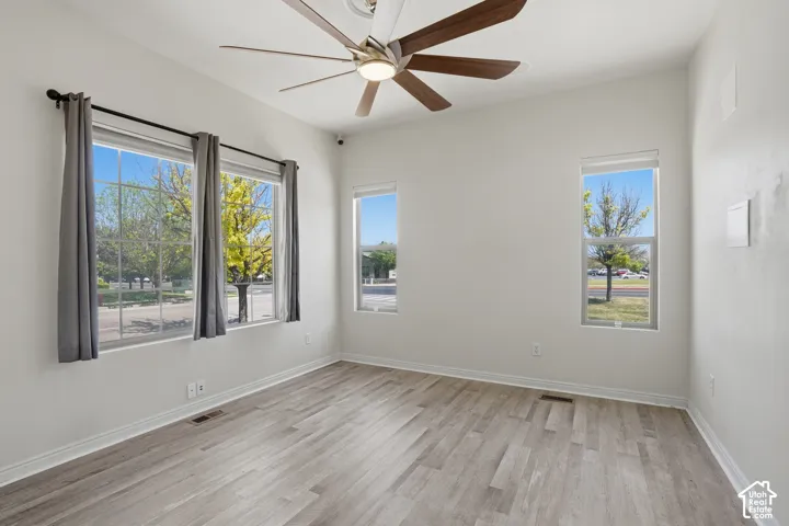 Spacious room featuring wood-finish flooring and multiple windows. Can be a bedroom, office, or flex space