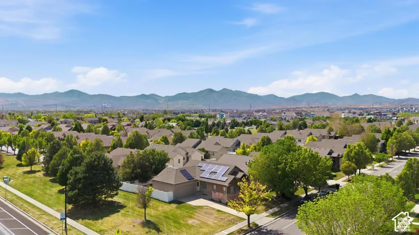Residential neighborhood featuring established homes with solar panels, mature trees, and mountainous terrain in the distance