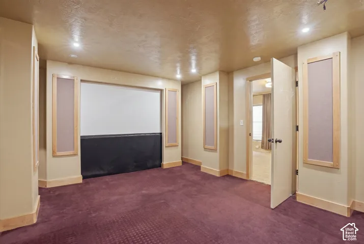Can also Media room featuring a recessed projection screen, wall-mounted acoustic panels, recessed lighting, and patterned carpeting