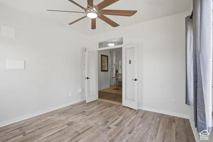 Room featuring wood-finish flooring, white walls, and a contemporary ceiling fan with wood-look blades