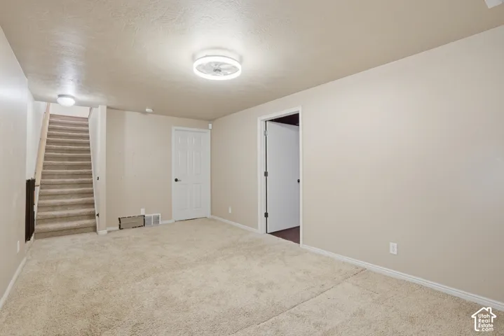 Carpeted room featuring a staircase with carpeted treads, neutral wall paint, and white trim