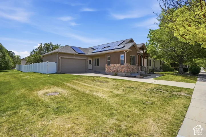 Single-story residence featuring solar panels, an attached two-car garage, and a concrete driveway