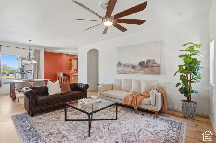 Spacious living area featuring wood-finish flooring, a contemporary ceiling fan, and a wide arched entryway