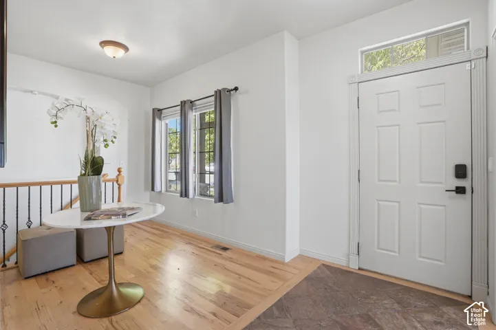 Entryway featuring a white paneled door with transom window, light wood-finish flooring, and a decorative wrought iron railing