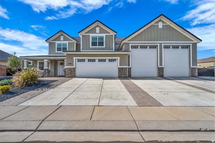 Contemporary two-story residence featuring a three-car garage, stone façade accents, and a covered entry
