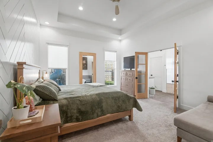 Bedroom featuring a tray ceiling with recessed lighting, wood-finish ceiling fan, and carpeted flooring