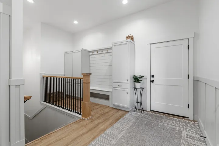 Entryway featuring wood-finish flooring, recessed lighting, and a built-in mudroom bench with storage cabinetry and coat hooks