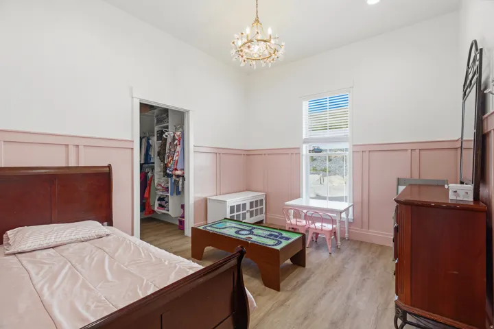 Spacious room featuring wood-finish flooring, a chandelier fixture, and a built-in closet with shelving