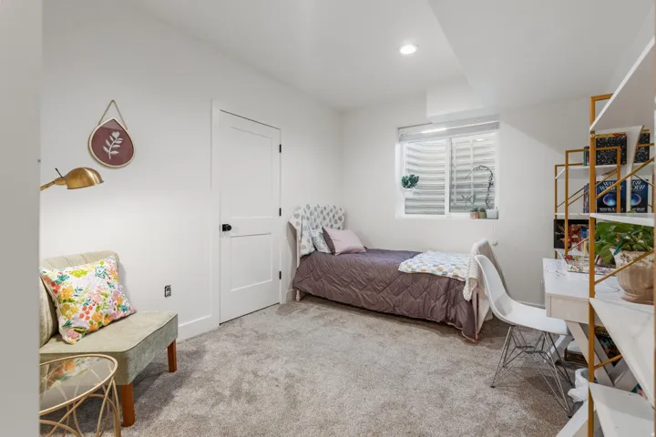 Carpeted room with a white door, recessed lighting, and a well window featuring horizontal blinds