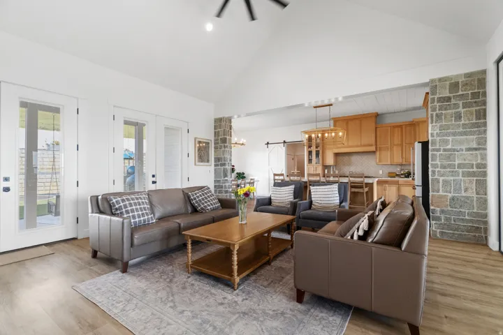 Vaulted ceilings highlight this living area featuring wood-finish flooring and multiple glass-paned doors