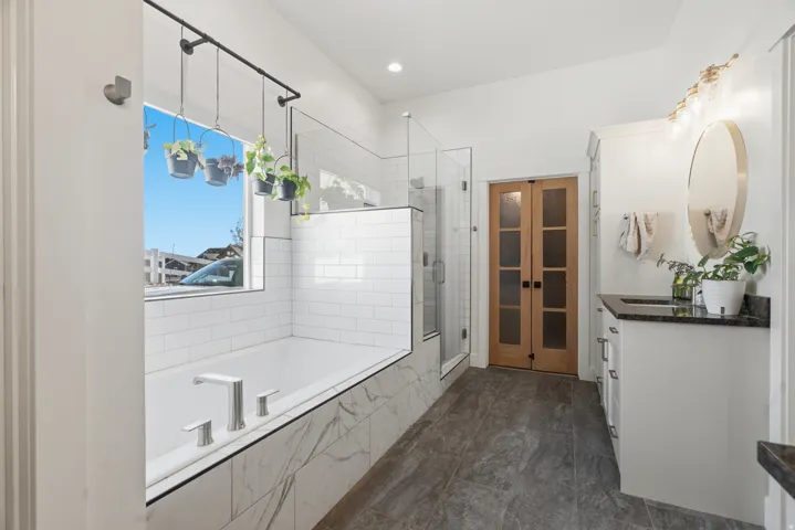 Sleek bathroom featuring a built-in tub with marble-look paneling and subway tile surround