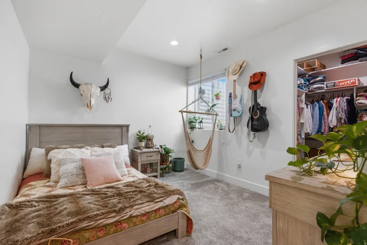 Carpeted room with a built-in closet featuring shelving and hanging rods, a single window, and a recessed ceiling light
