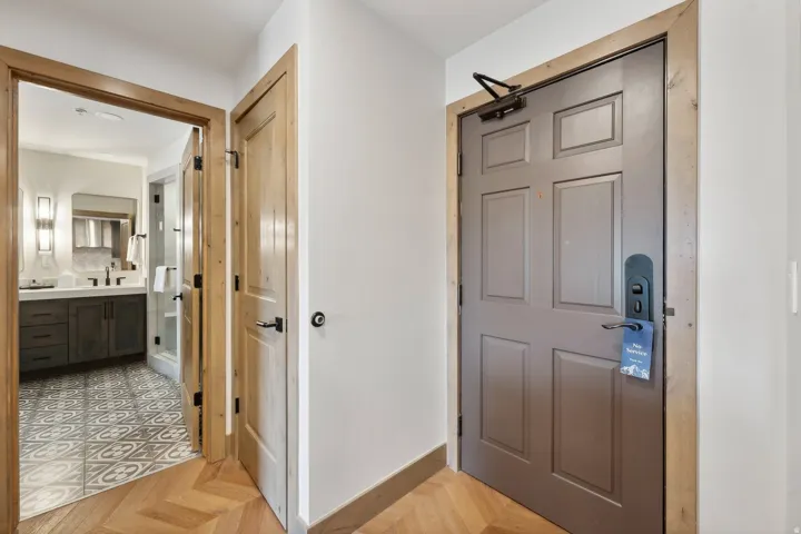 Herringbone wood-finish flooring extending into the hallway, featuring a solid panel door with dark hardware