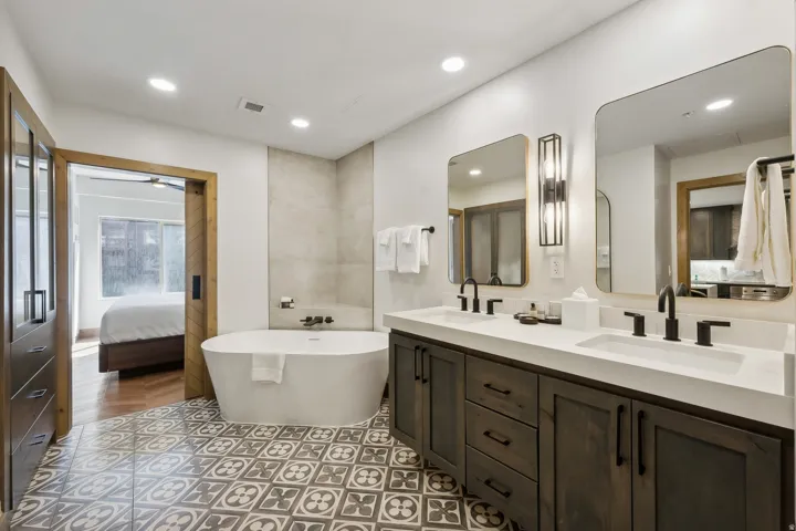 Bathroom featuring a freestanding soaking tub, dual vanity with undermount sinks, and patterned floor tiles