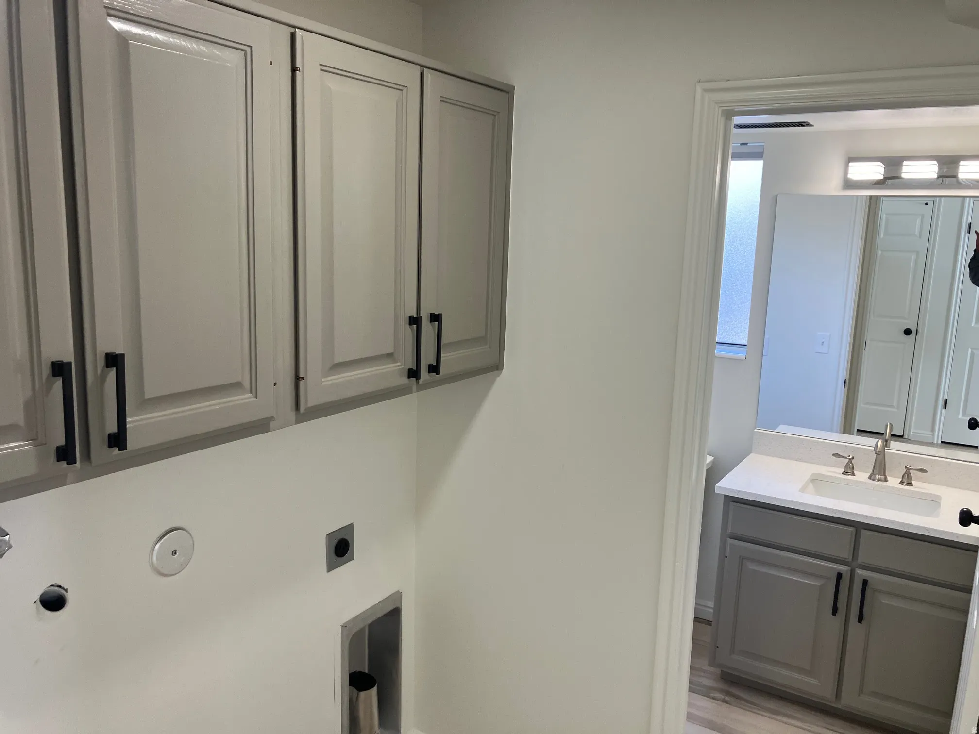 Laundry area featuring overhead cabinetry with matte black hardware