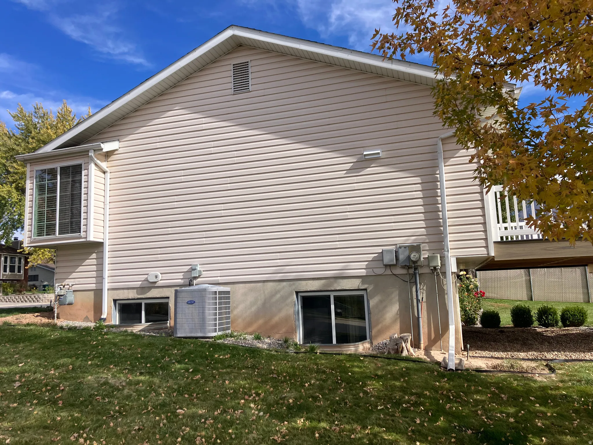 Light beige vinyl siding exterior with a white trim bay window