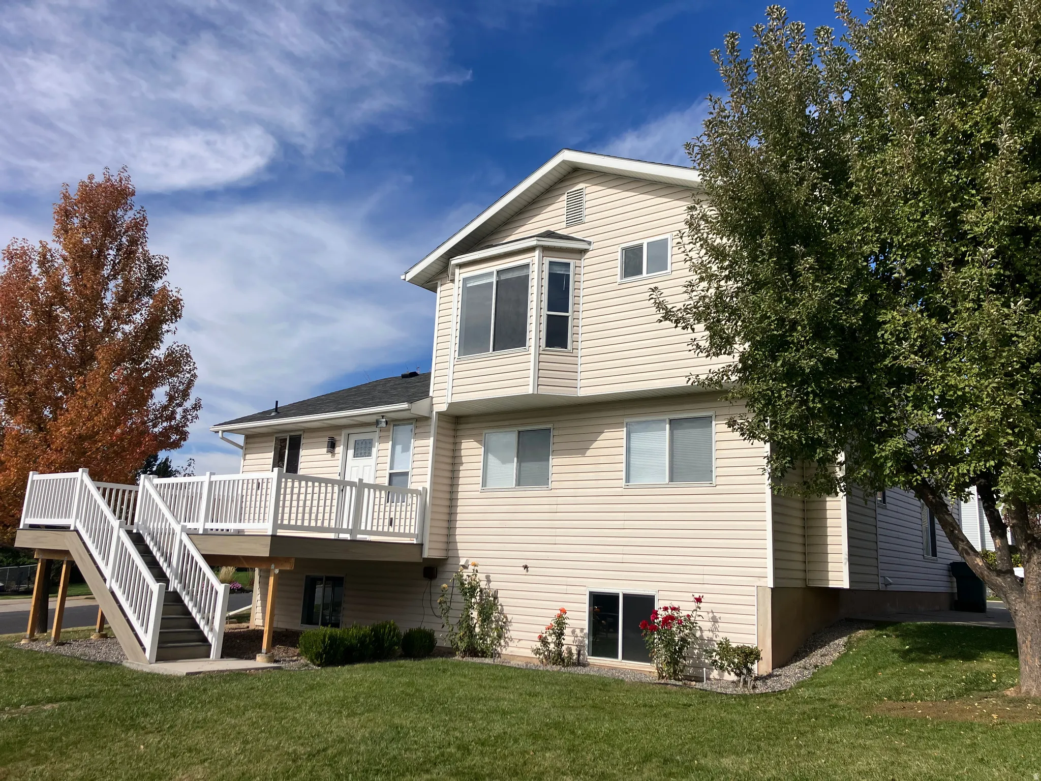 Exterior with light-colored siding, multiple windows, and a multi-level deck featuring white railings and stairs