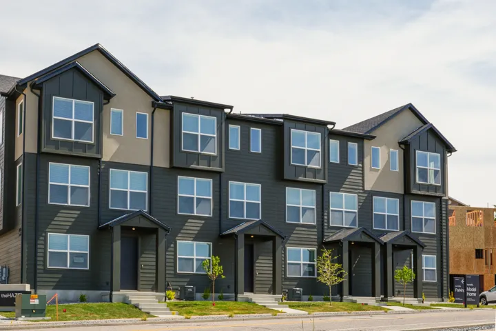 Modern townhome facade featuring dark siding and light stucco accents