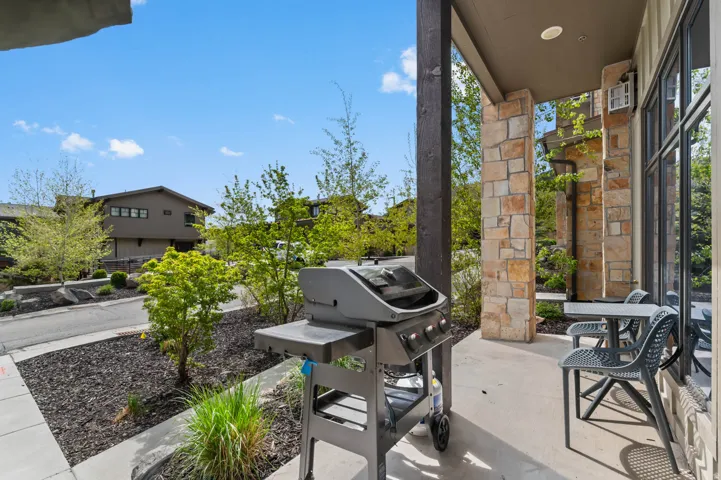 Covered patio featuring stone veneer accents, a dark wood support column, and large windows