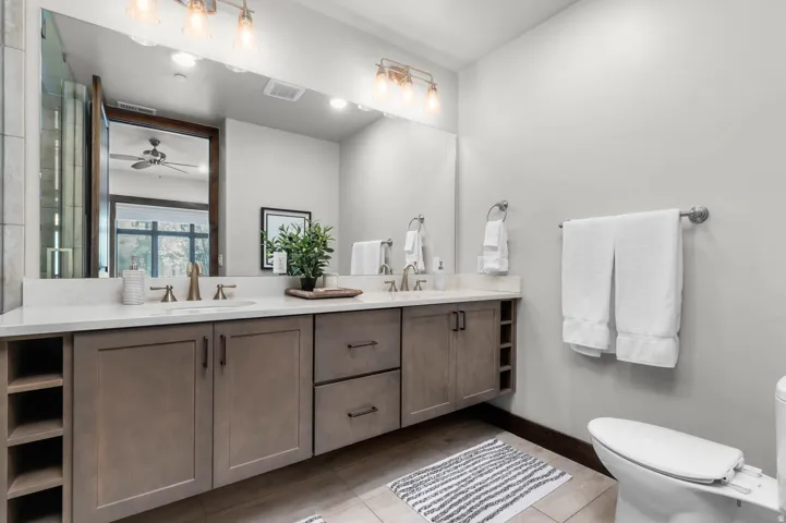 Dual vanity with light-toned cabinetry, integrated shelving, and undermount sinks