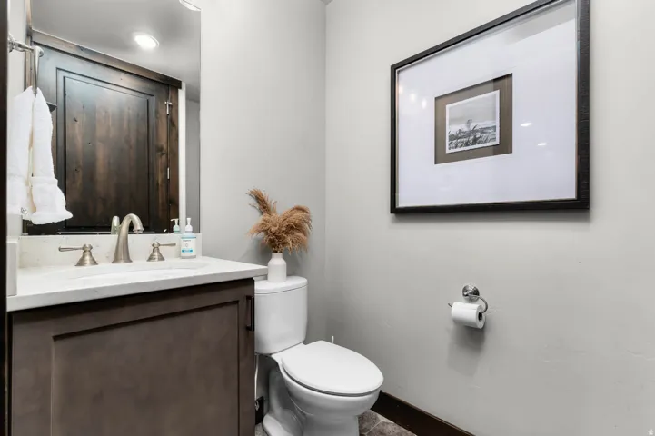 Powder room featuring a single vanity with stone countertop, undermount sink, and brushed nickel faucet