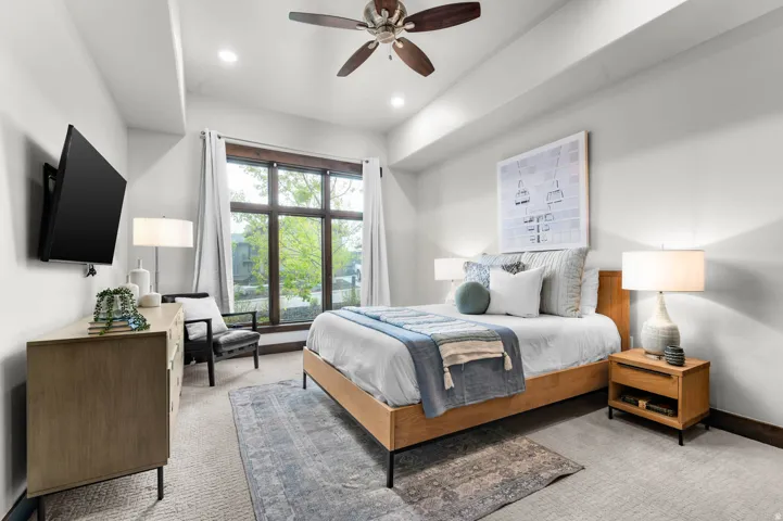 Bedroom featuring a wide window with dark wood framing, a tray ceiling, and recessed lighting