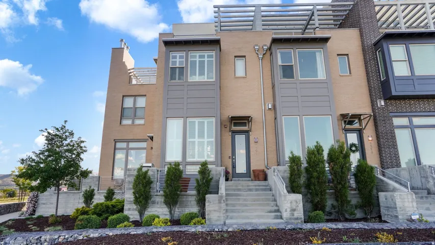 Contemporary multi-story townhome featuring a brick and panel exterior